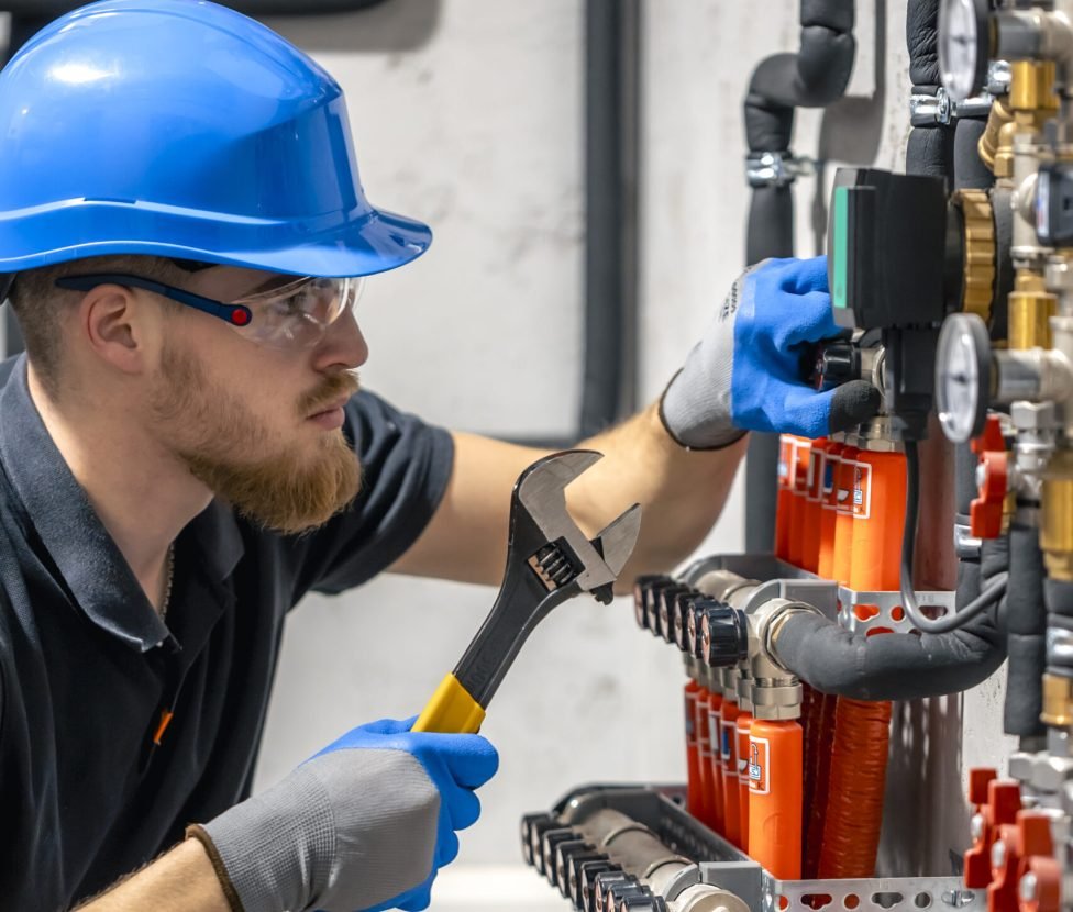 The technician checking the heating system in the boiler room. Adjusting heating valves in a residential building. A plumbing and heating technician works.